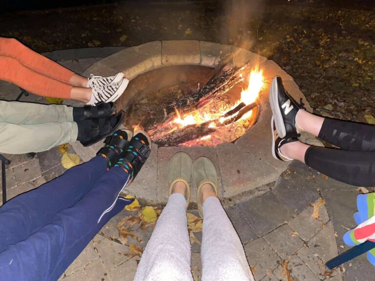 Friends with feet up around a fire pit, color photo