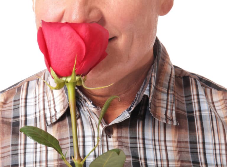 Older man holding rose by nose