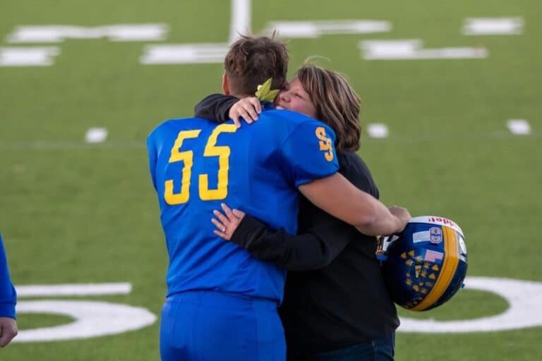 Mother hugging football player son, color photo
