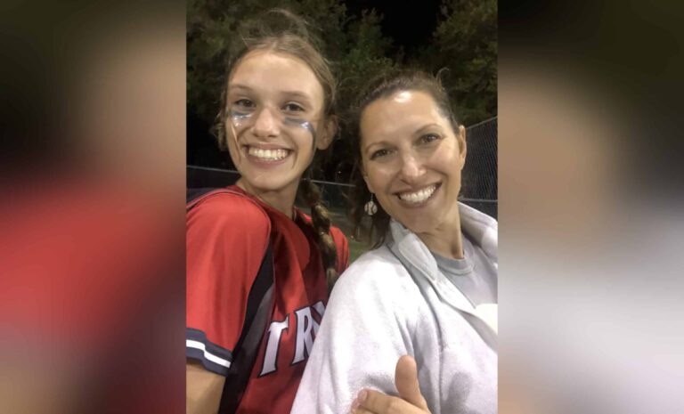 Mother with daughter in softball uniform, color photo