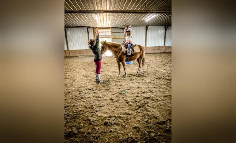 Teen coach with young rider on horse, color photo