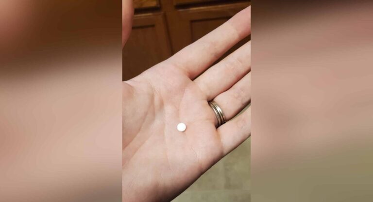 Woman holding white pill in hand, color photo