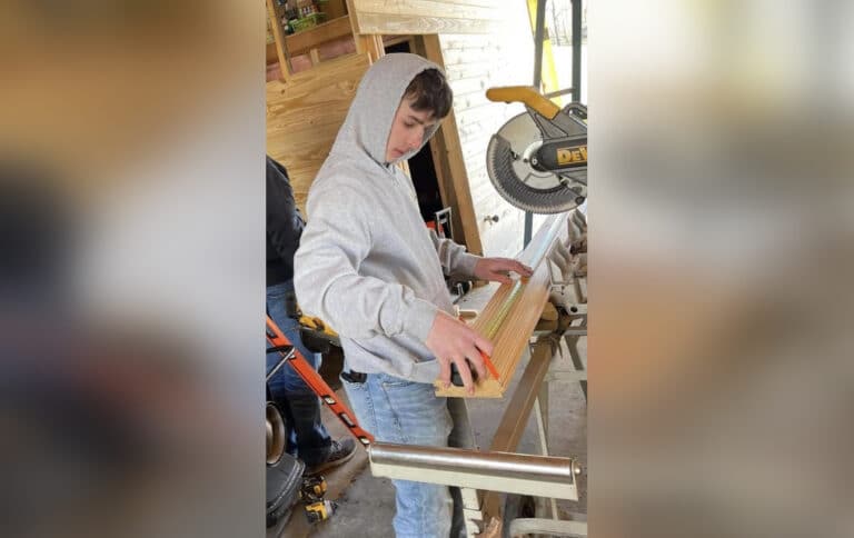 Teen boy working at table saw