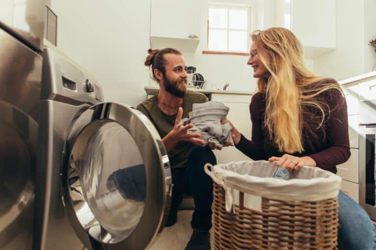 Couple doing laundry in front of washing machine