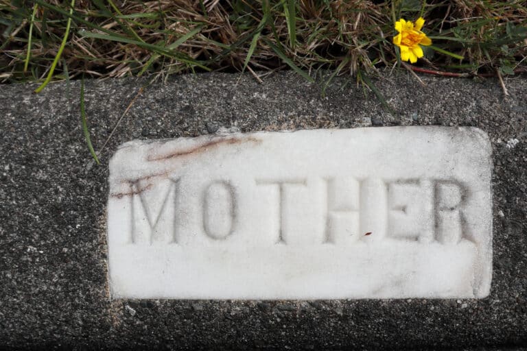 Grave stone that says "mother" with a yellow flower