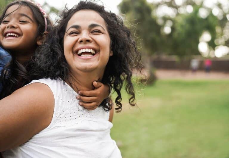 Woman laughing with young girl on her back