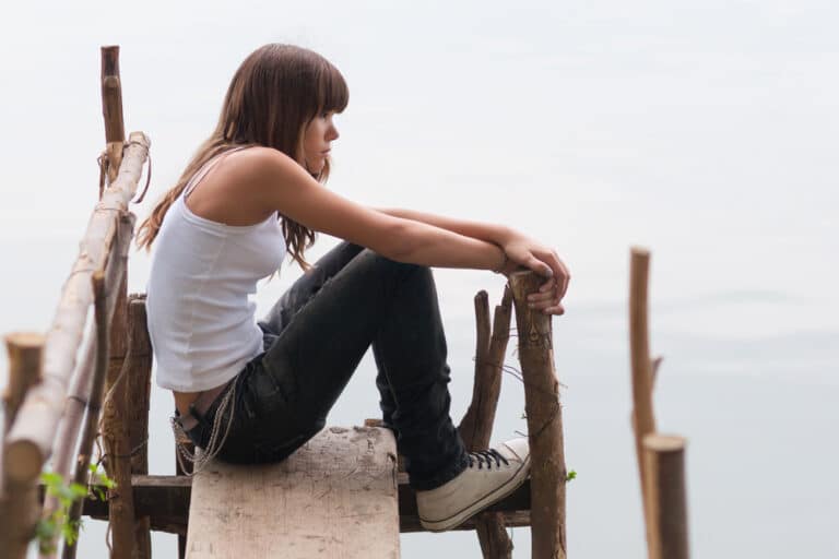 Teen girl sitting alone on a dock