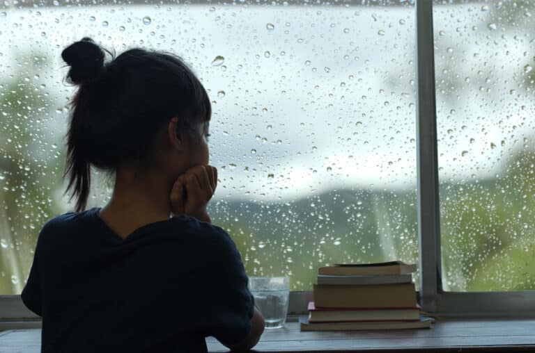 Young woman looking out rainy window
