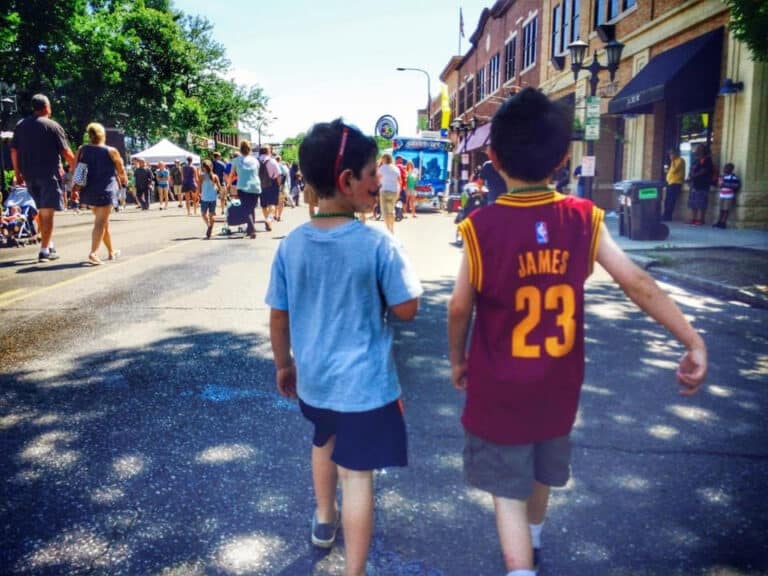 Two kids walking down the street together, color photo