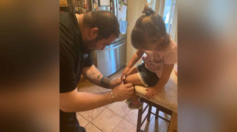 Daddy putting bandage on little girl's leg, color photo