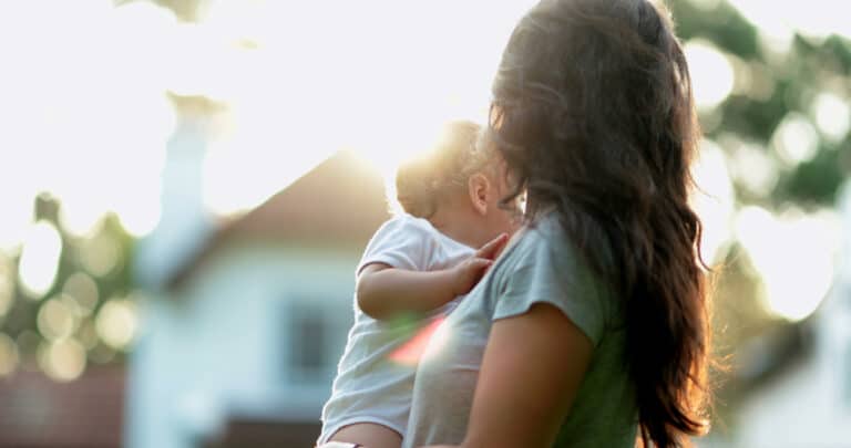 Mom holding baby looking at sun