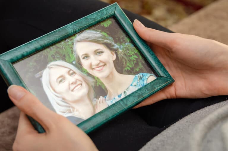 Hands holding framed photo of two smiling women