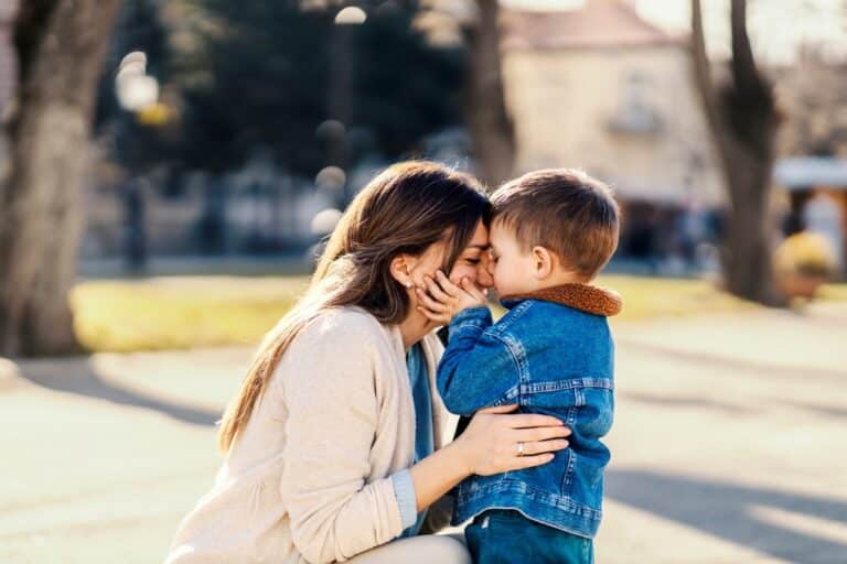 Son kissing his mother's forehead, outdoor photo