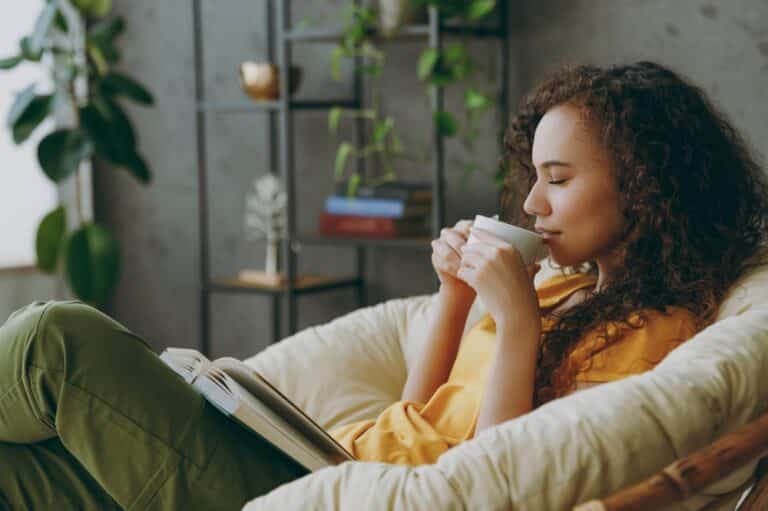 Woman sipping coffee and reading a book at home relaxed