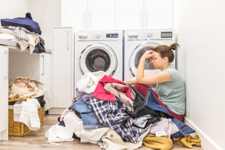 Woman sitting in pile of laundry with head in hands