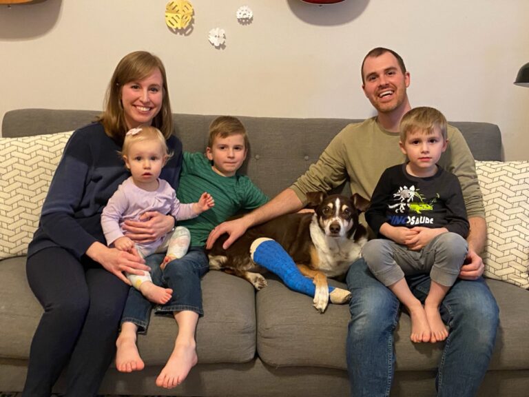 Family sitting on couch with dog, color photo