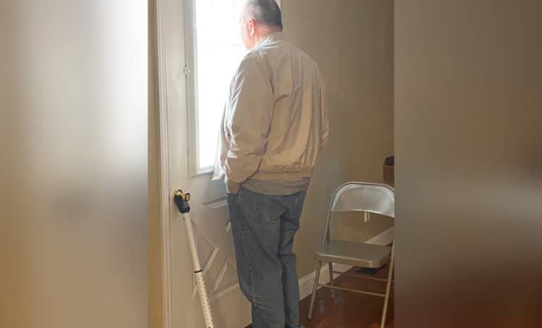 Older man looking out window on door