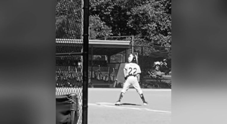 Boy standing on first base, black-and-white photo