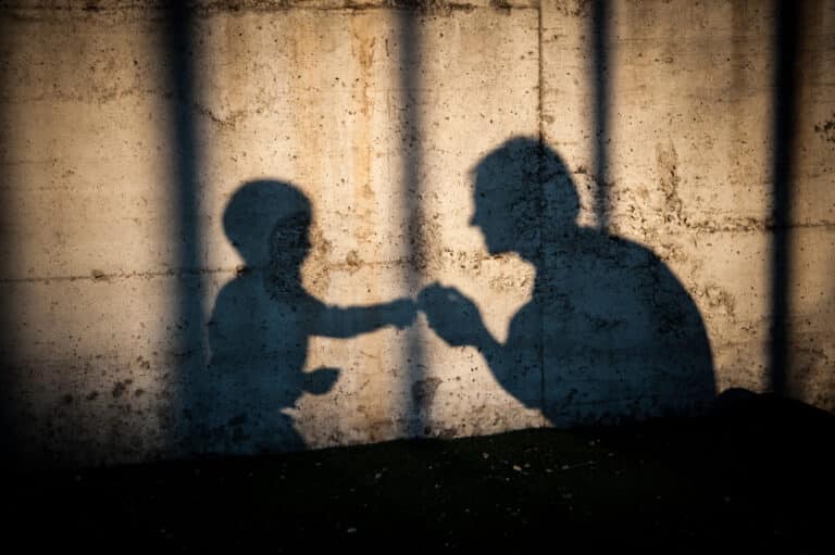 Woman crouched down looking at young boy, shadows on the wall