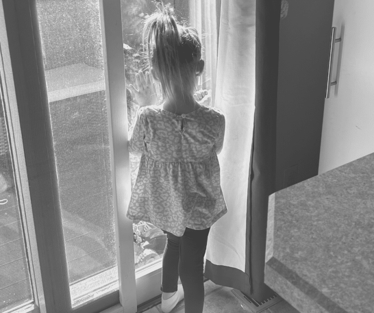 Little girl looking out window, black-and-white photo