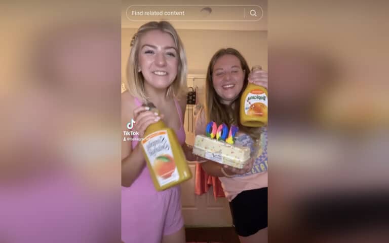 Two college girls holding orange juice and cake smiling in TikTok video still