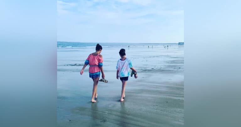 Mother and tween daughter walking on beach, color photo