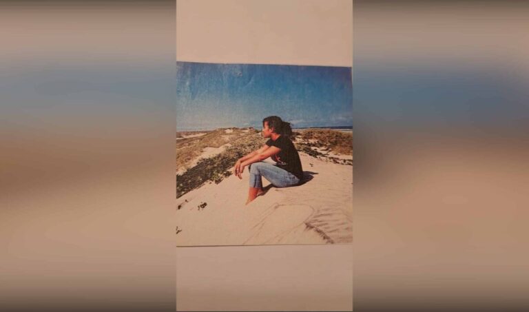 Young girl sitting on sand dune, color photo