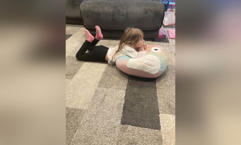 Little girl lying on living room floor, color photo