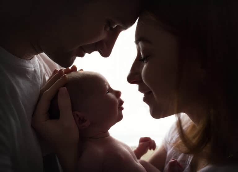Mother and father with newborn baby between them, profile close ups