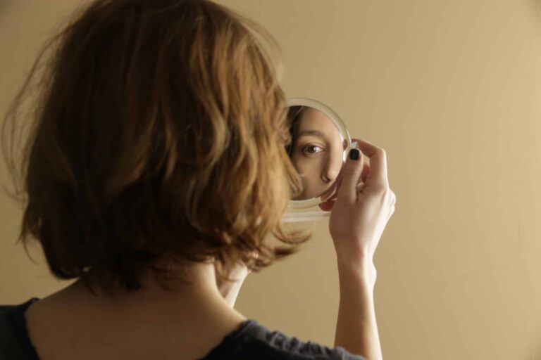 Woman looking at reflection in small handheld mirror