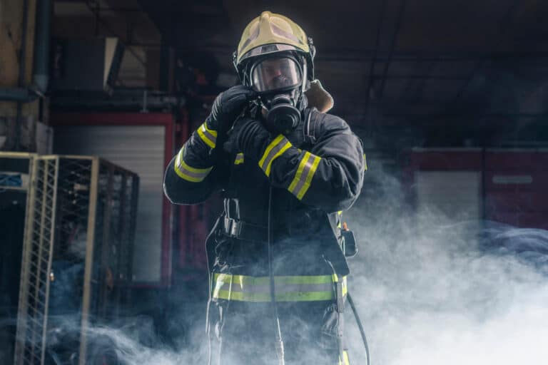 Portrait of a fireman wearing full firefighting gear walking through smoke