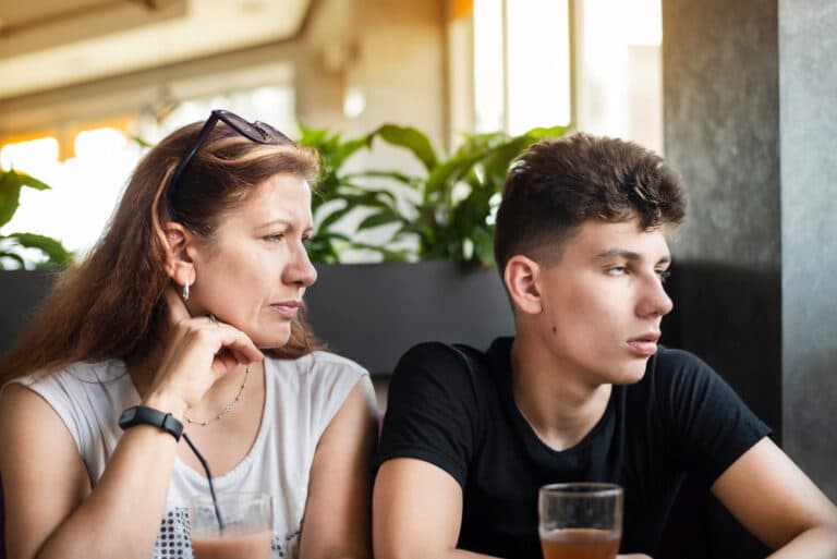 Mom looks at teen boy who is looking away and rolling his eyes