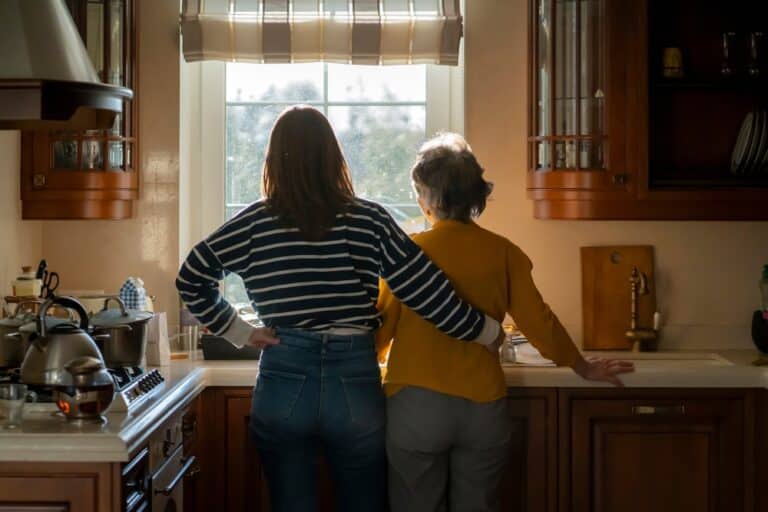 Woman and grandmother do dishes at a sink window