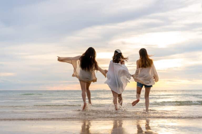 Group of 3 friends walking on beach at sunset