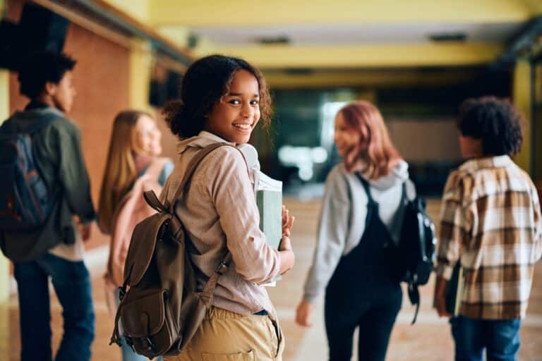 Teen girl walking down hall with other students at high school