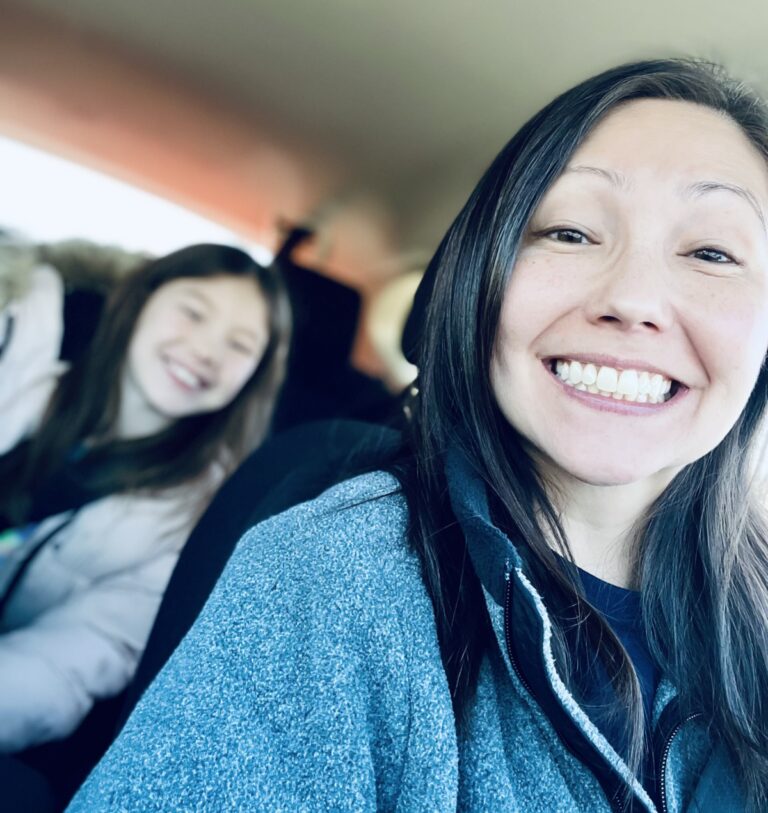 Mom in driver's seat with tween daughter in backseat, color photo