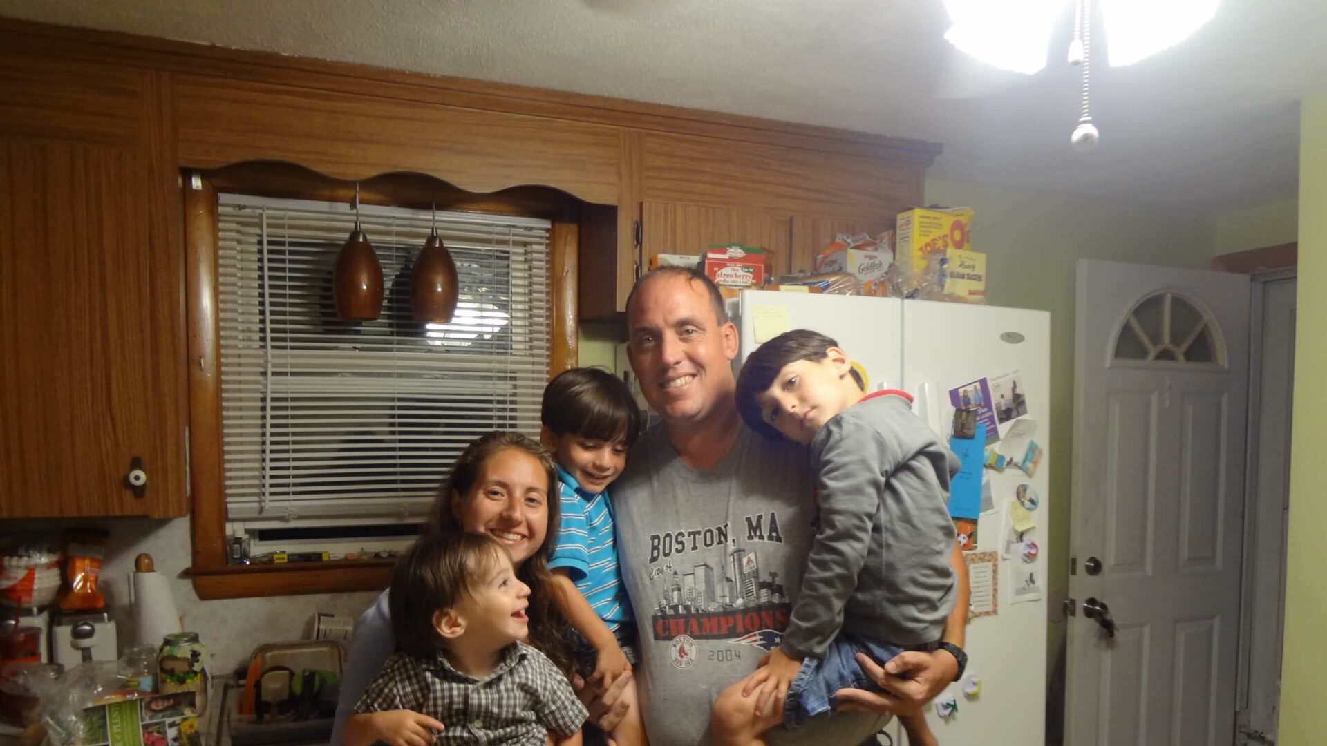 Family with three small boys standing in kitchen, color photo