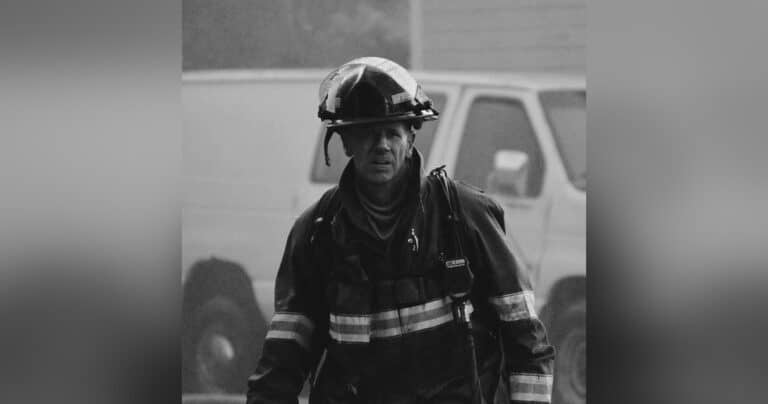 Firefighter in gear walking, black-and-white photo