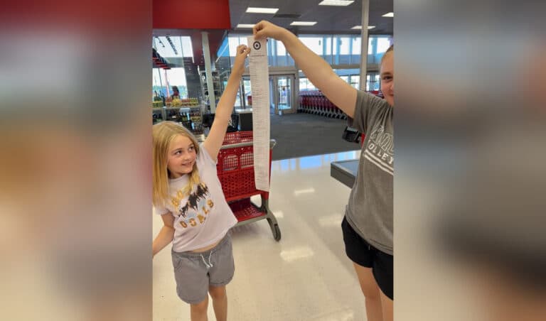 Two girls hold up long receipt in store