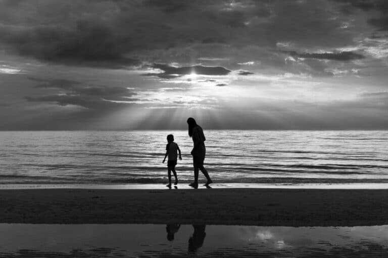 Mother and child walking by water in black and white photo