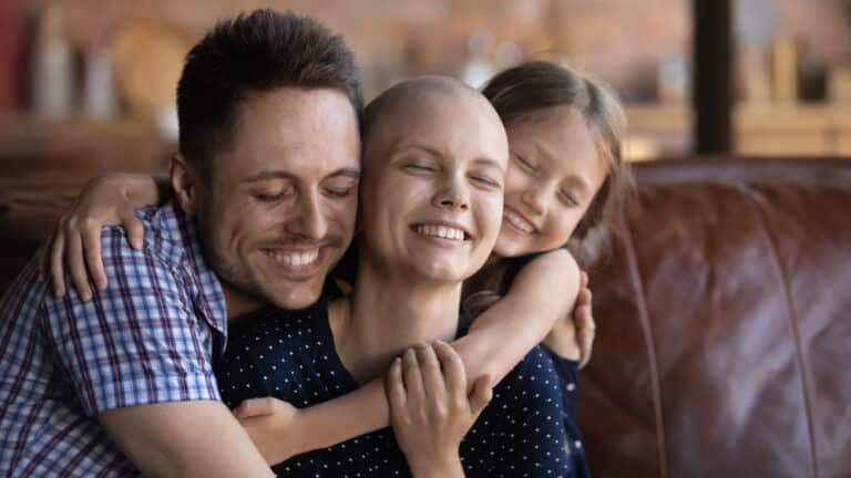 Cancer survivor being hugged by man and child