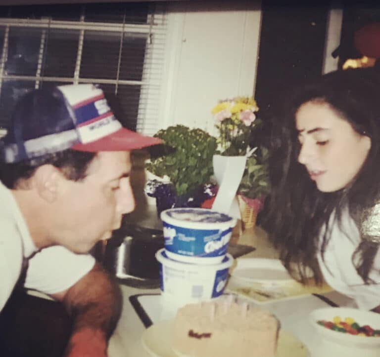 Old, color photo of father and tween daughter blowing out candles