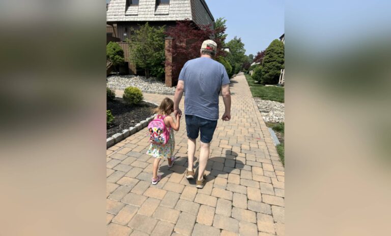 Little girl and grandpa walking down sidewalk, color photo
