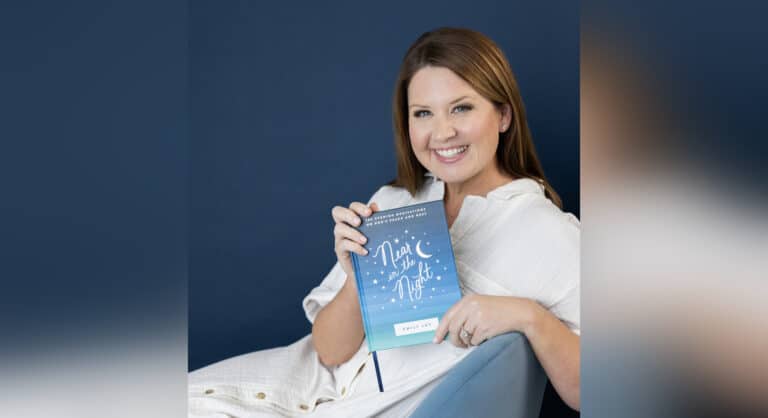 Woman wearing white outfit and sitting in a chair holding book with blue cover