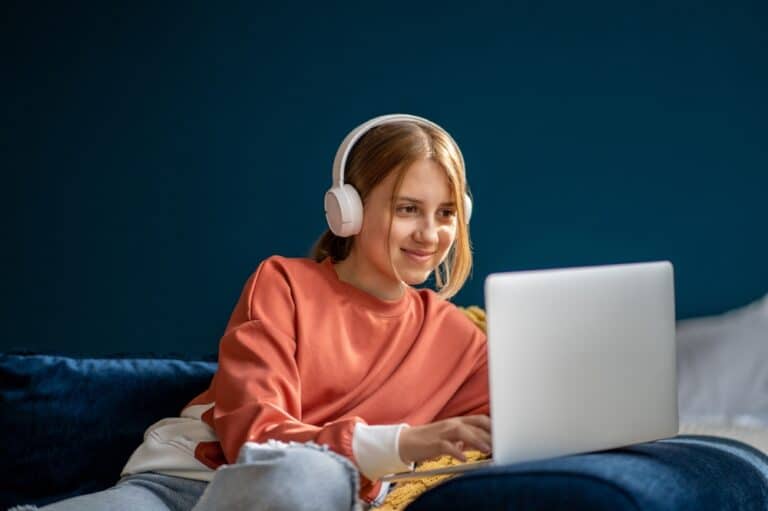 Teen girl wearing headphones looking at laptop computer