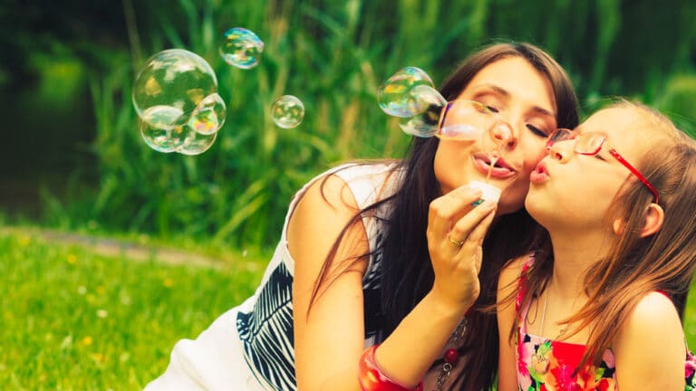 Mother and daughter blowing bubbles