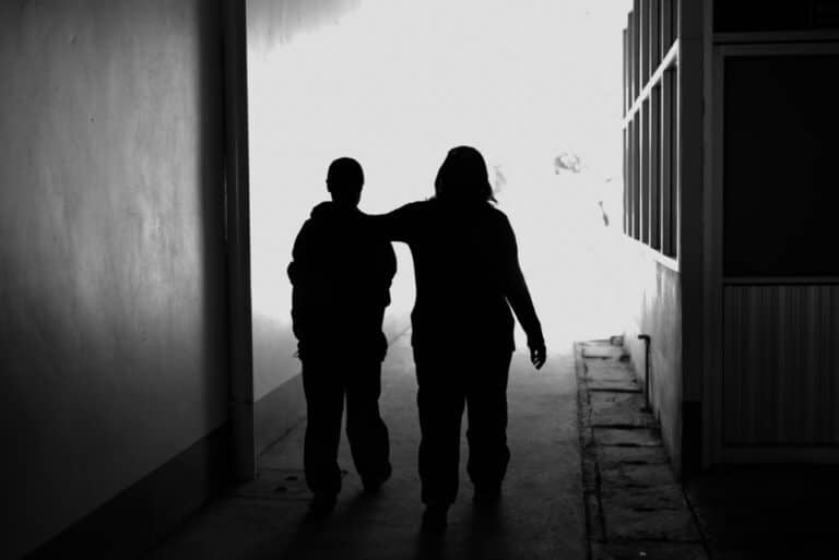 Two people walking down tunnel with arms around each other