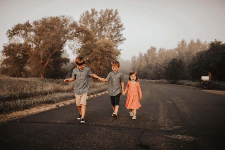 Two little boys and their sister walking down a gravel road, color photo