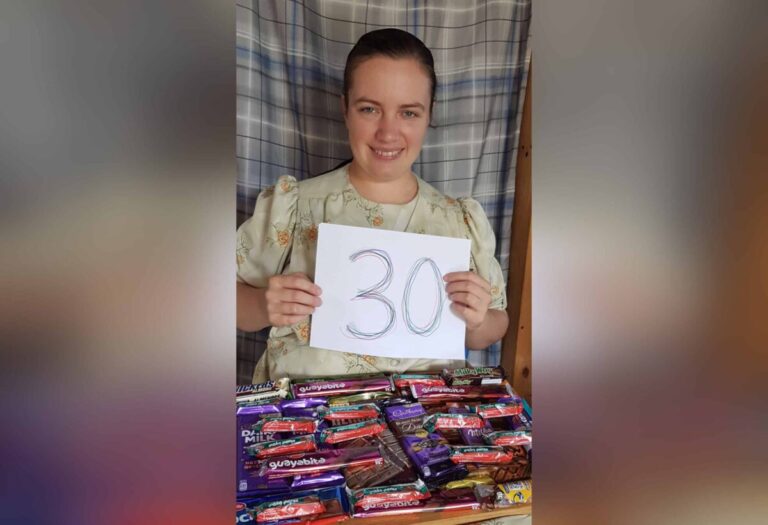 Woman holding a sign with the number 30 and chocolates, color photo