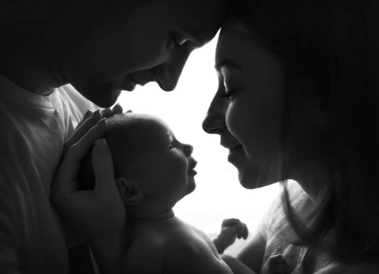 Newborn gazing at mother with father smiling down